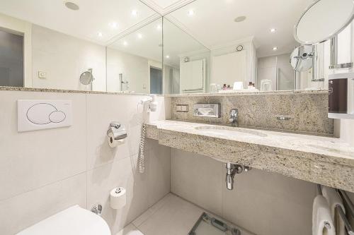 a bathroom with a sink and a toilet and a mirror at EUROPÄISCHER HOF Bad Gastein in Bad Gastein