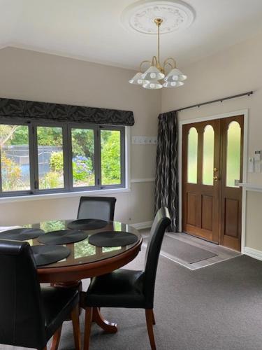 a dining room with a table and chairs and a window at Emerald Haven in Upper Hutt