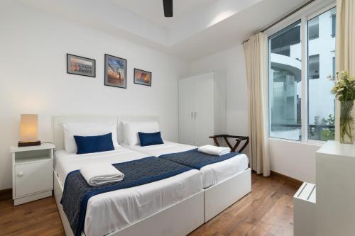 a white bedroom with a large bed and a window at Oceanfront Condominium - Nilaveli in Nilaveli