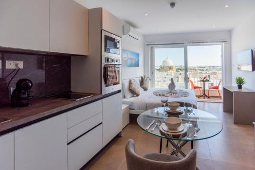a kitchen and living room with a bed and a table at Orbis Boutique Studios by Holi in Qormi