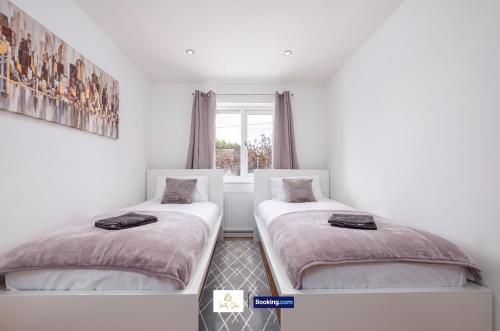 two beds in a room with a window at Centrally Located 3 Bedroom House By Trinity Stays Short Lets & Serviced Accommodation Cambridge in Cambridge