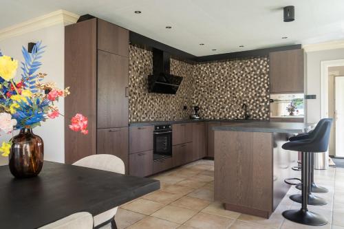 a kitchen with wooden cabinets and a table with a vase of flowers at Mooie, luxe woning aan het water 7 persoons VP005 in Heinkensand