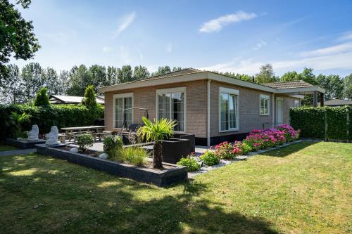 a house with a garden in front of it at Mooie, luxe woning aan het water 7 persoons VP005 in Heinkensand