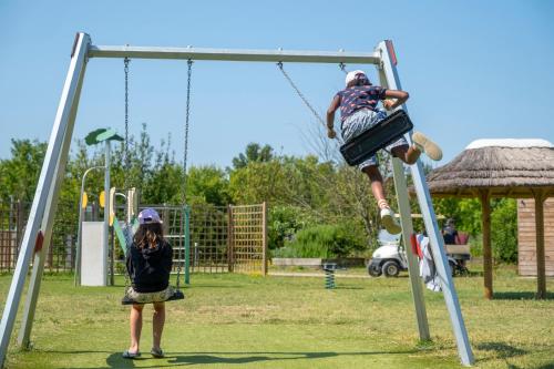 un homme et une fille jouant sur une balançoire dans l'établissement Camping Le Plan d'Eau, à Saint-Yrieix-sur-Charente