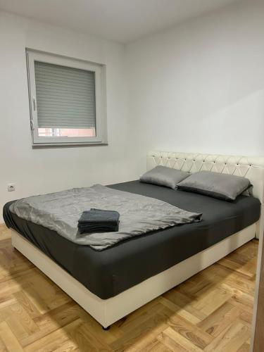 a large bed in a white room with a window at Apartman Moskva in Teslić