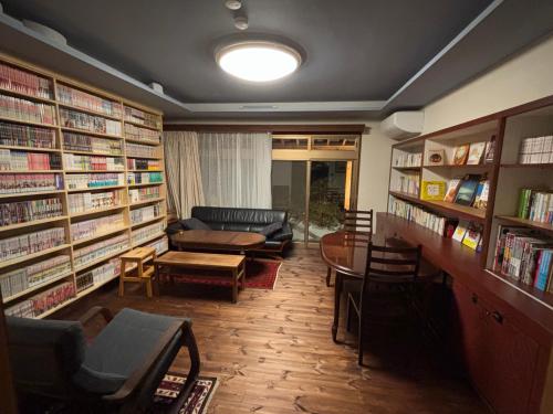 Matsukawaにある離れの宿 かぶろの庭のソファ、テーブル、本が備わる図書室