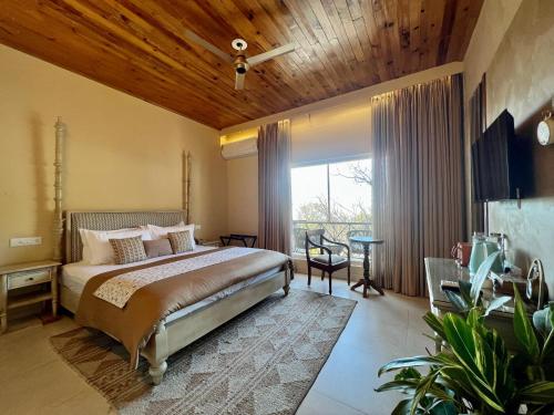 a bedroom with a bed and a large window at IRAH by Parvatah in Bīr