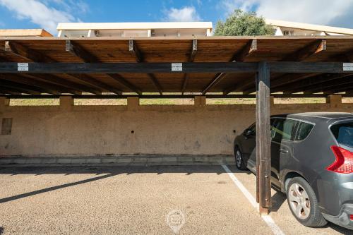 a car parked in a parking lot with a wooden roof at Asfodelo 21 in Is Molas 