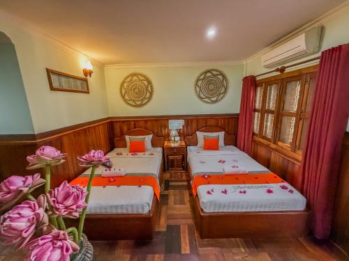 two beds in a room with flowers in a room at Siem Reap Center Hotel in Siem Reap