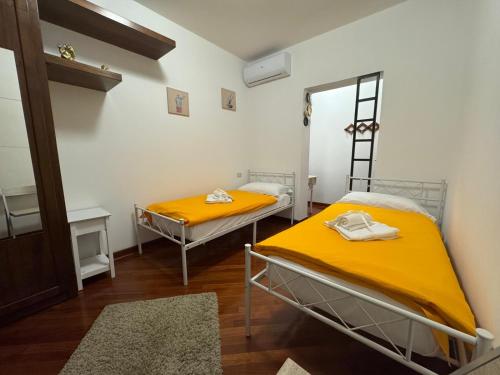 two beds in a room with yellow sheets at Chiarelli House in Udine