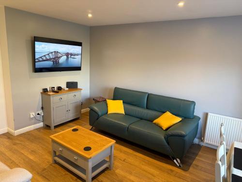 a living room with a couch and a tv on the wall at Dunfermline 2 Bed Flat Fully Furnished in Dunfermline