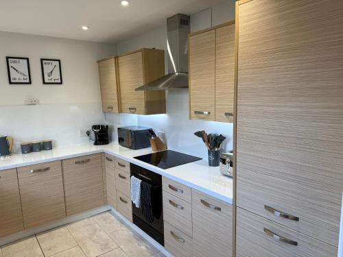 a kitchen with white counter tops and wooden cabinets at Dunfermline 2 Bed Flat Fully Furnished in Dunfermline