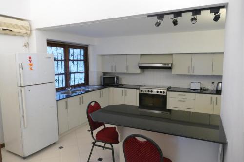 a kitchen with white appliances and red chairs in it at Embassy Suites in Colombo