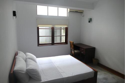 a bedroom with a bed and a desk and a window at Embassy Suites in Colombo