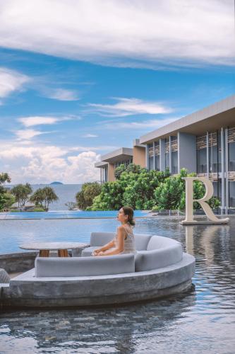 a woman sitting in a boat in the water in front of a building at Renaissance Pattaya Resort & Spa in Na Jomtien