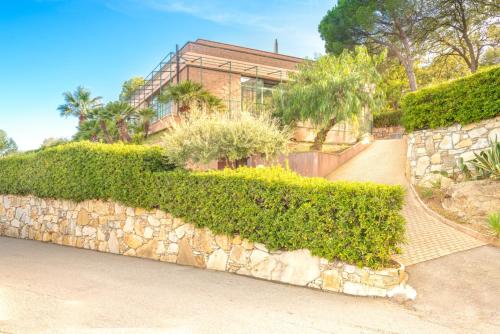 a stone wall with hedges and a building at Villaggio Colombo NUOVA GESTIONE in Marina dʼAndora