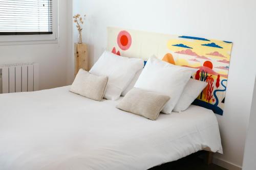 - un lit blanc avec des oreillers blancs et un tableau dans l'établissement Terrasse face à l'océan pour 4 personnes, à Plouguerneau