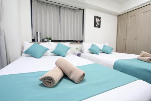 a bedroom with two beds with towels on them at LUANA in SHIBUYA in Tokyo