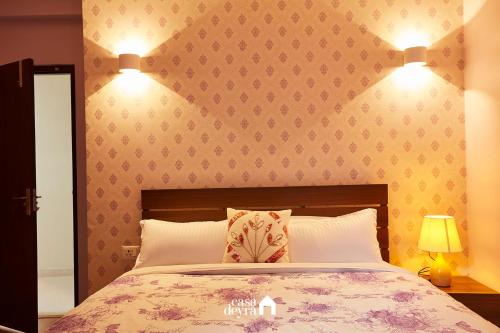 a bedroom with a bed and two lights on the wall at Jhamel Apartments 2 by Casa Deyra in Pātan