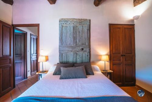 - une chambre avec un lit avec une tête de lit en bois et deux lampes dans l'établissement Studio 2, à Saint-Montan