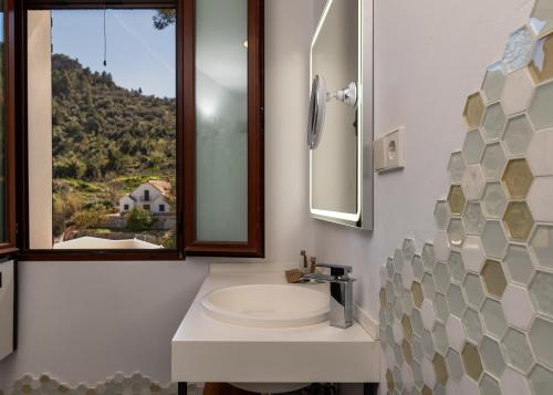 a bathroom with a sink and a mirror and a window at LA CASA DEL PANTANO in La Vall de Laguar