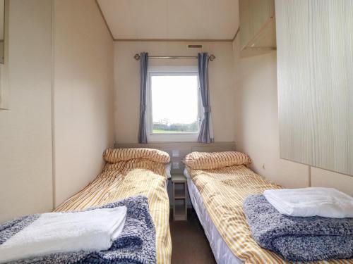 three beds in a small room with a window at Little Trevorrick Caravan in Wadebridge
