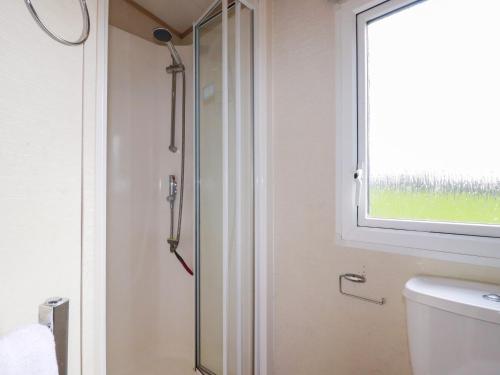 a glass shower in a bathroom with a window at Little Trevorrick Caravan in Wadebridge