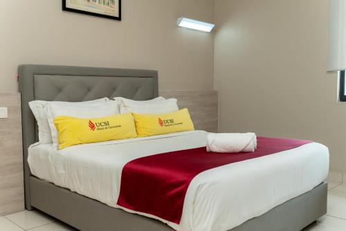 a bed with two yellow and red pillows on it at Le Quadri Kuala Lumpur By UCSI Hotels in Kuala Lumpur
