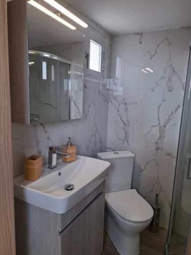 a white bathroom with a toilet and a sink at Kozani room with a view! in Kozani