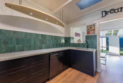 a kitchen with black cabinets and green tiles at Summers Cottage - Port Noarlunga in Port Noarlunga