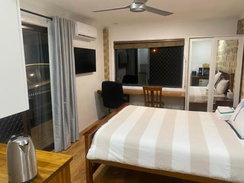 a bedroom with a bed and a desk and a kitchen at The Palms in Parrearra