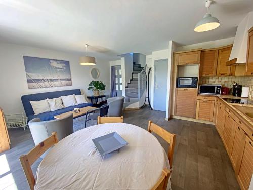 une cuisine et un salon avec une table avec un ordinateur portable dessus dans l'établissement Longère au calme à Larmor-Plage, proche plage et commerces, jardin privatif et parking couvert - FR-1-349-101, à Larmor-Plage