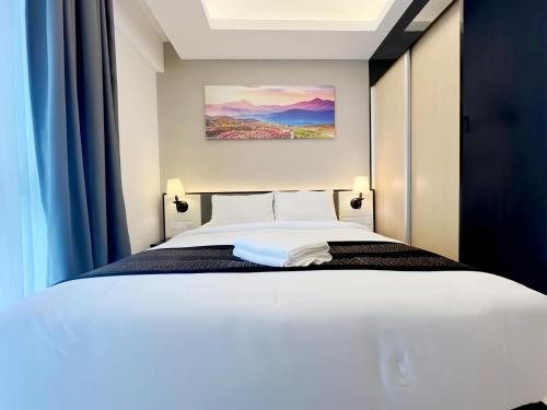 a bedroom with a white bed with blue curtains at Grand Ion Genting Highlands in Genting Highlands