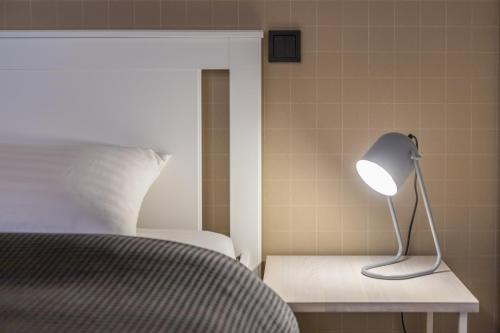 a lamp sitting on a table next to a bed at B2 Apartments in Klaipėda