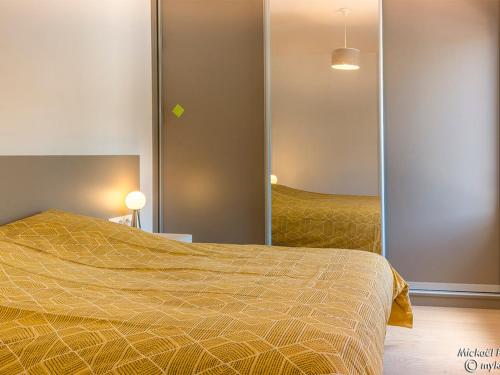 une chambre avec un lit et un miroir dans l'établissement LARMOR-PLAGE : T2 en résidence de standing avec terrasse et parking, à deux pas de la plage et des commerces - FR-1-349-182, à Larmor-Plage