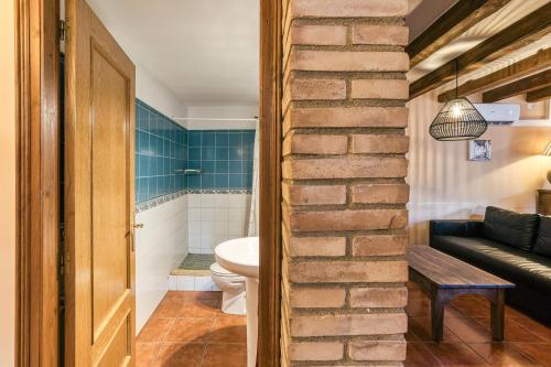 a bathroom with a toilet and a brick wall at Cal Matalí in Espolla