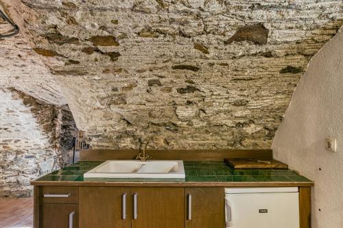 a kitchen with a sink and a stone wall at Cal Matalí in Espolla