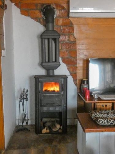 a wood stove in a room with a tv at Etno kompleks Orahovac - Vajat Lastavica in Arandjelovac