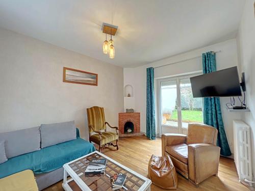 un salon avec un canapé et une cheminée dans l'établissement Charmante maison 1930 centre Hennebont, déco actuelle, terrasse, jardin clos, 2 chambres, wifi inclus - FR-1-349-204, à Hennebont