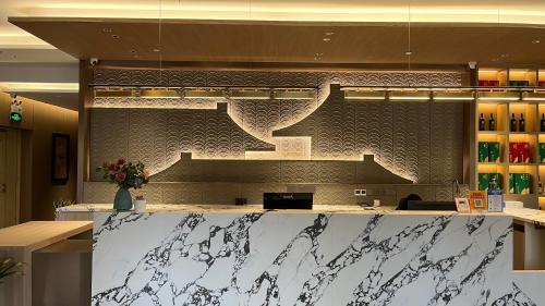 a lobby with a counter with a staircase on the wall at 西安隐逸雅致酒店The Elegant Hotel- 南二环店South 2ndRing Road in Xi'an