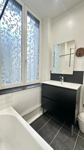 a bathroom with a tub and a sink and a mirror at Le repère de la cathédrale - Metz Hypercentre in Metz