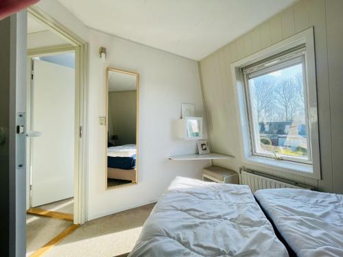 Schlafzimmer mit einem Bett, einem Fenster und einem Spiegel in der Unterkunft Liguster 74* in Nieuwvliet