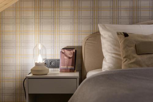 a bed with a book on a table next to a lamp at B2 Apartments in Klaipėda