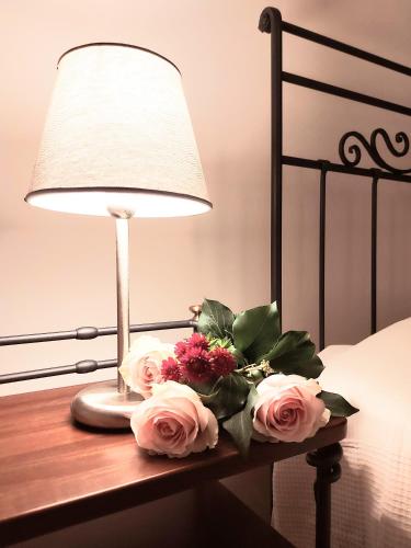 a bouquet of flowers on a table next to a lamp at Arena in Love - Centre Rooms in Verona