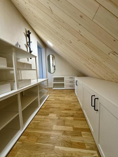 an attic kitchen with white cabinets and wooden ceilings at Independence square apartments II in Mažeikiai