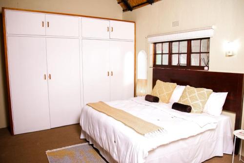 1 dormitorio con 1 cama grande y armarios blancos en Ukhanya resort, en Midrand