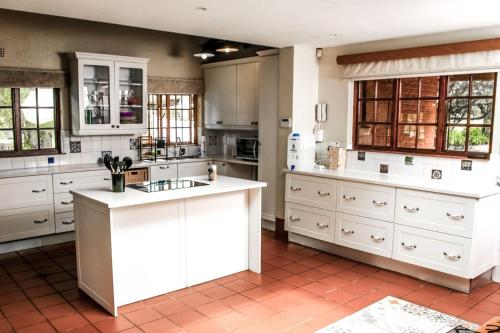 una cocina con armarios blancos y encimeras blancas en Ukhanya resort, en Midrand