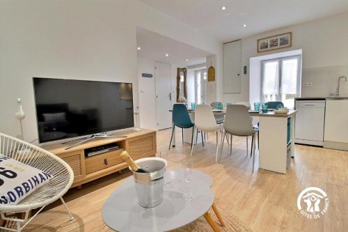 - un salon avec une grande télévision et une table avec des chaises dans l'établissement L'effet mer, à Gâvres