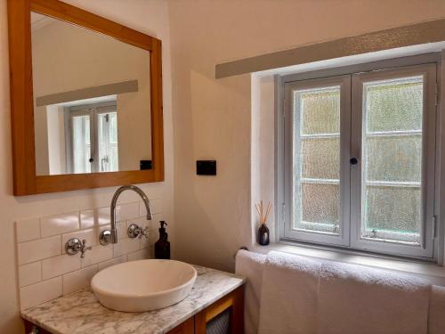 a bathroom with a sink and a mirror and a window at Goat Square House - Historic Row Cottages in Tanunda
