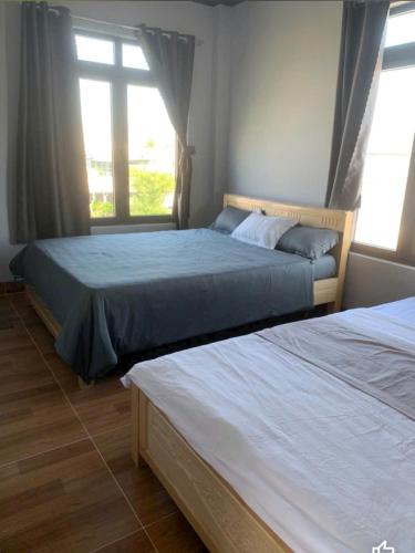 two beds in a bedroom with two windows at Nomad homestay in Ninh Hải